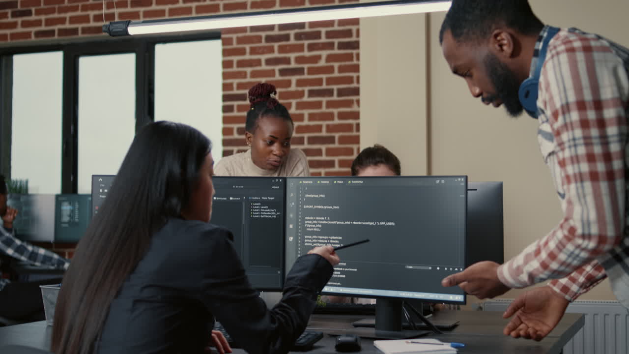 Mixed programmers team working on group project on multiple screens showing running code