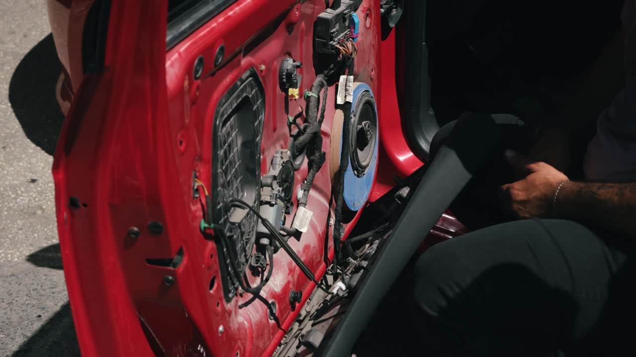 Auto service worker disassembles car door for speaker repair. Automobile industry