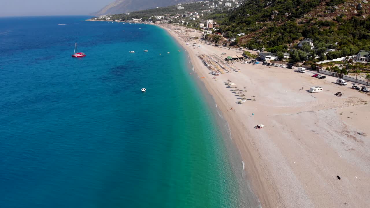 Wide sandy beach washed by calm clear water of blue azure Ionian sea in Albanian coastline