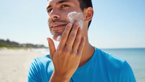 a young man applying sunscreen on his face while enjoying a sunny day at the beach, emphasizing the importance of skin protection against uv rays