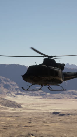 military helicopter flying over a desert landscape