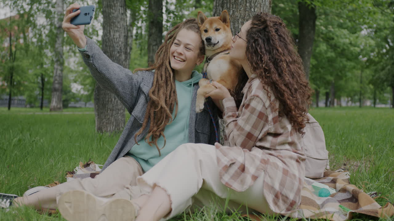 Two Women Taking a Selfie with a Dog in a Park