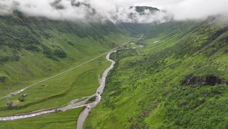 Exuberante-Y-Verde-Valle-De-Kvassdalen-Que-Conduce-Al-Paso-De-Montaña-De-Vikafjellet-Desde-Voss,-En-El-Oeste-De-Noruega,-Antena-Cinematográfica-De-Verano-Con-Parches-De-Nubes-Alrededor-De-Las-Cimas-De-Las-Montañas.