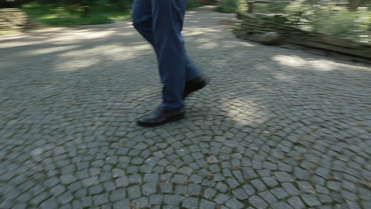 Close up of shoes and pants of a groom walking on the street.