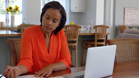 Front-view-of-mixed-race-mature-woman-working-on-laptop-on-desk-at-home-4k
