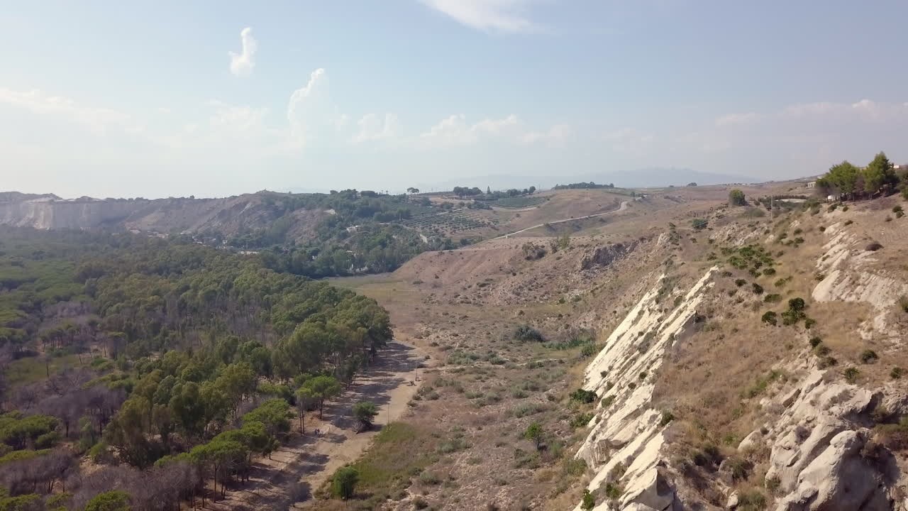 A drone shot of the countryside of Sicily - Italy. The camera slowly moves down revealing more of the sandstone cliff.