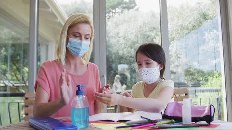 madre e hija usando máscaras faciales desinfectando sus manos en casa
