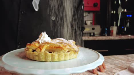 Lateinischer-Männlicher-Barista,-Der-Puderzucker-Auf-Einen-Apfelkuchenstrudel-In-Einem-Cafeteria-café-restaurant-In-Mexiko-Lateinamerika-Streut