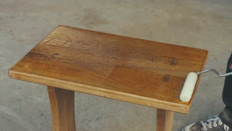 barnizando una pequeña mesa de roble de madera con rodillo, lapso de tiempo