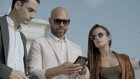 Front-view-of-focused-business-partners-looking-at-phone-screen