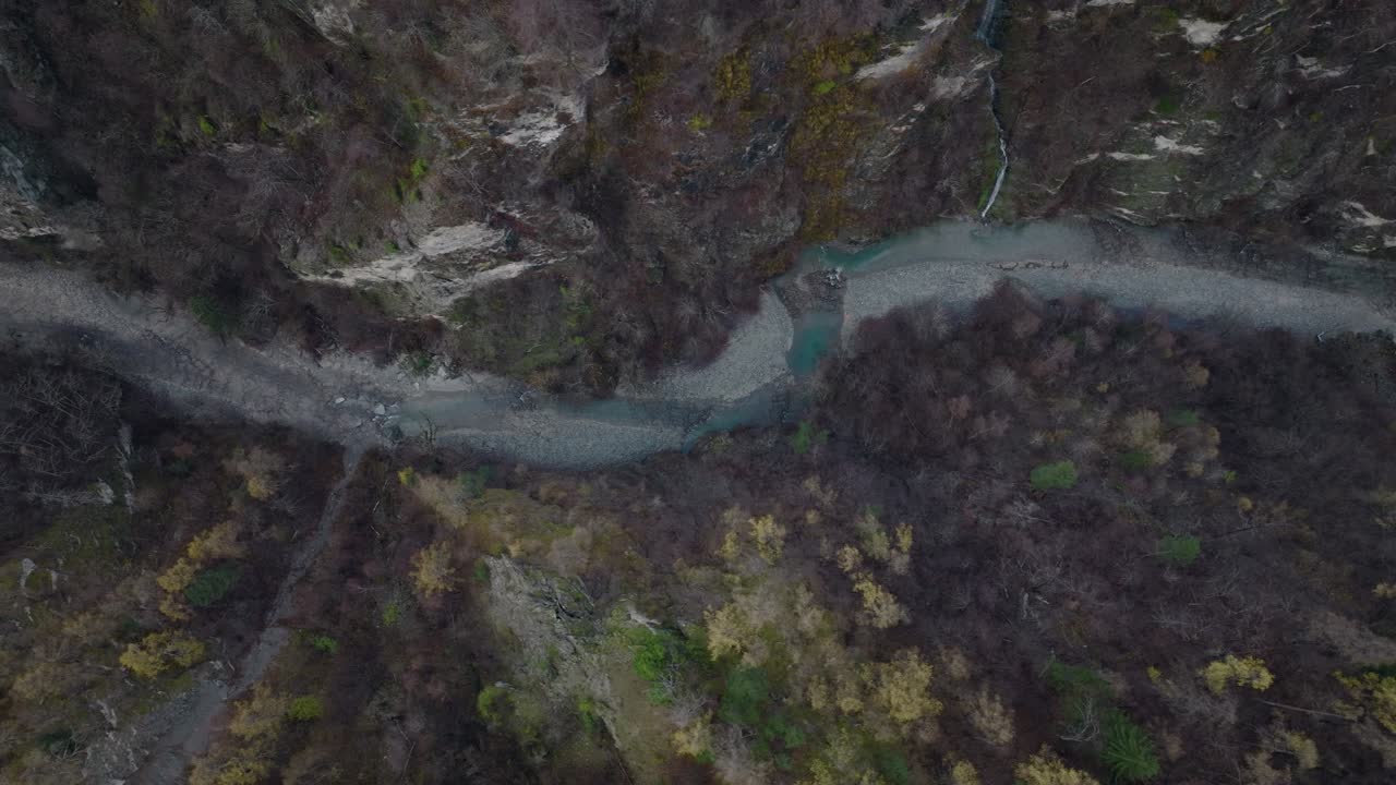 relajante toma aérea de arriba hacia abajo de un río que fluye en un paisaje invernal cambiante en suiza sobre un puente viejo