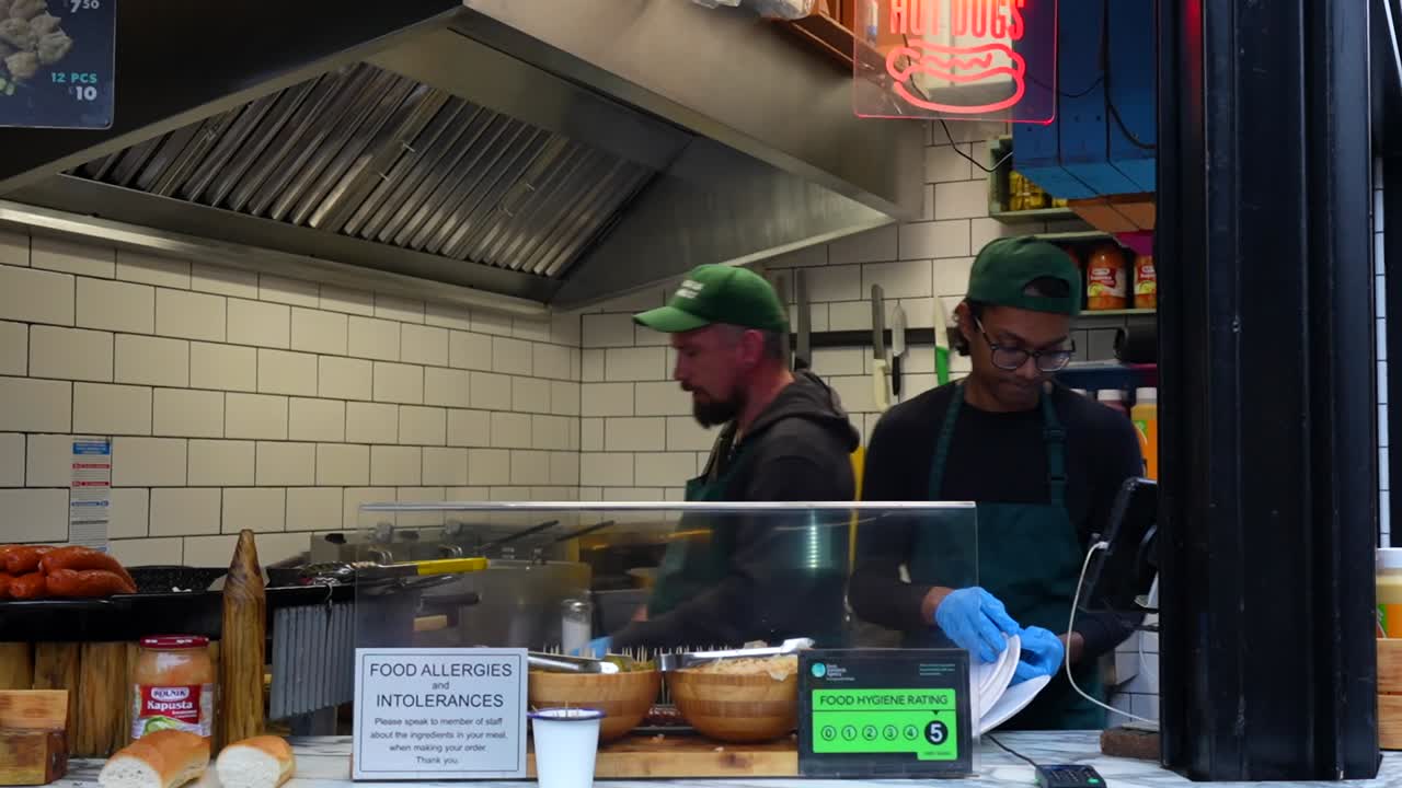 Two men prepare hot dogs at a food stand in Camden Town market, London, UK