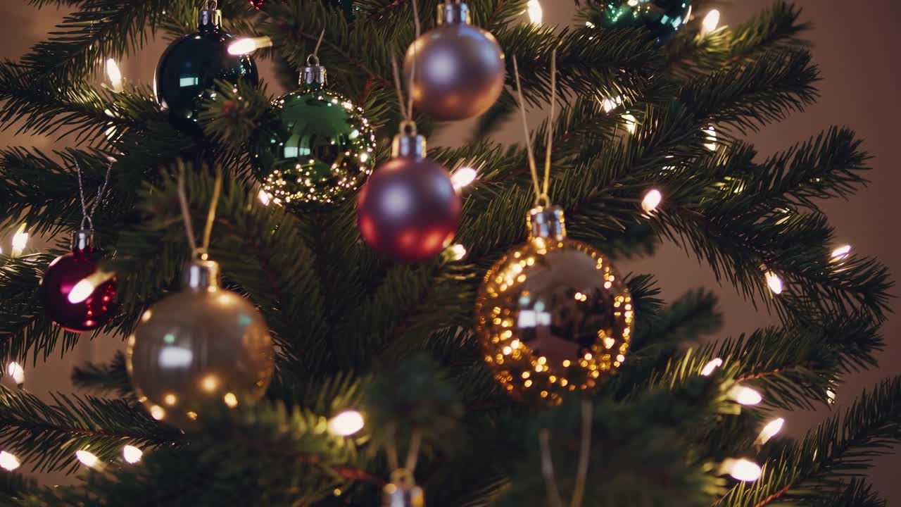 Close-up video angle of a Christmas tree adorned with colorful baubles and warm lights
