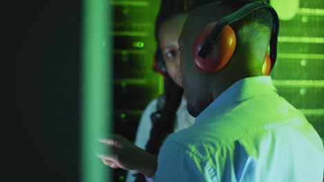 african american computer technicians wearing headphones working in business server room