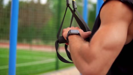 close up of male hands with smart watches holding rubber belt handles, ready for outdoors training