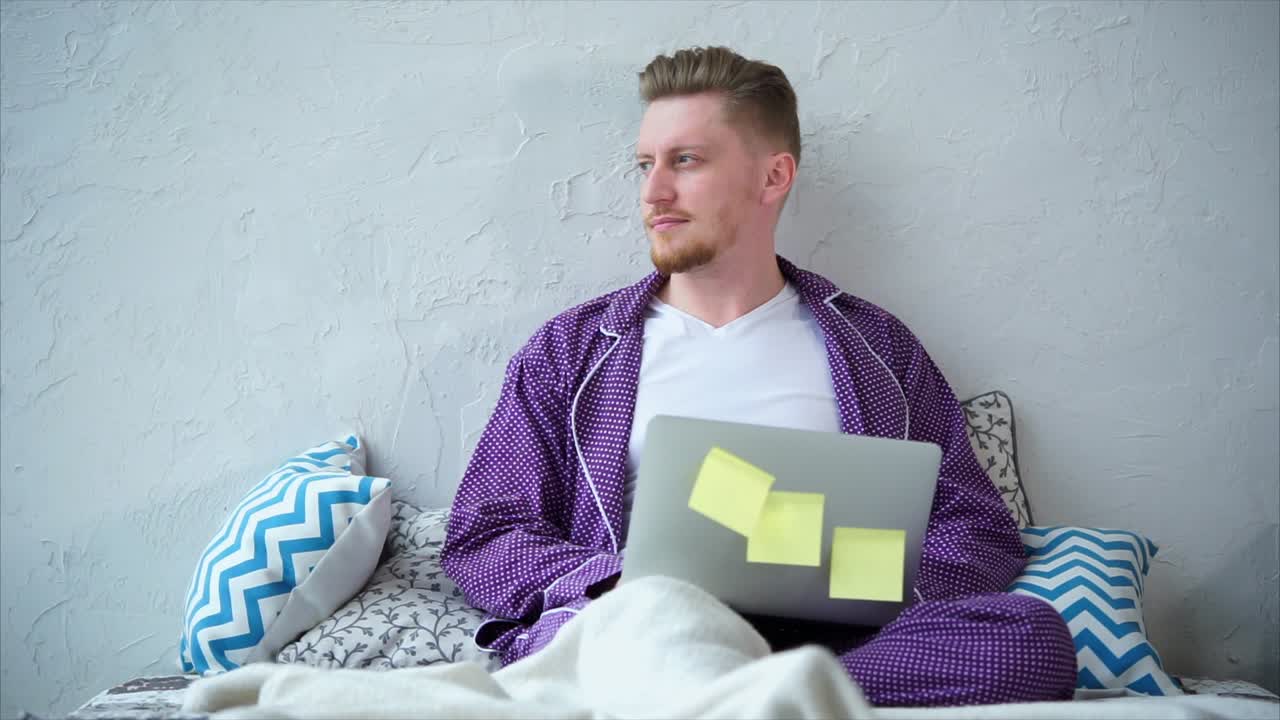 Man working on laptop in pajamas in bed