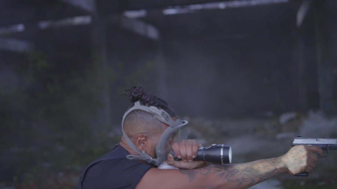 흑인 남성 장교가 총을 꺼내서 검색 조명을 휘두르며 연기가 나는 폐허를 스캔합니다.