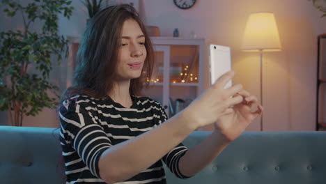 young woman taking a selfie on her phone at home