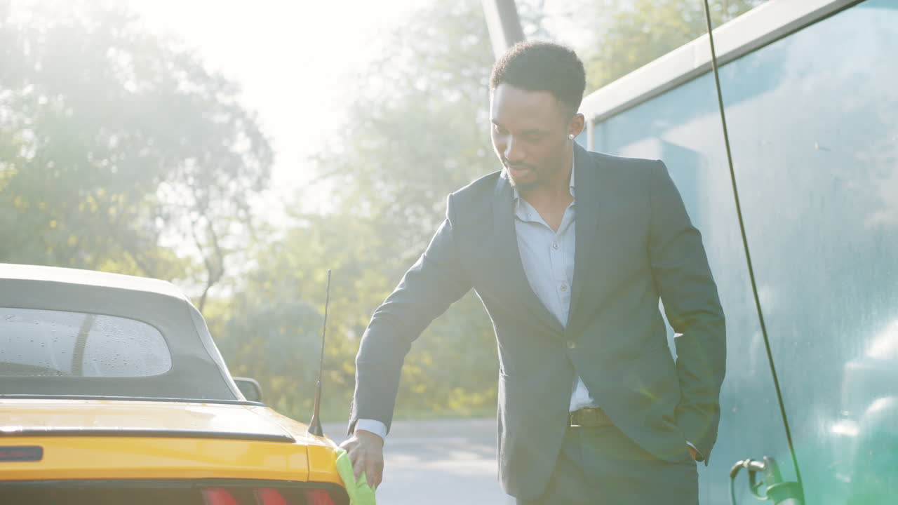 hombre de traje lavando un coche amarillo