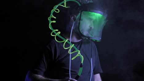 inclínate hacia arriba, el hombre vapea o fuma de un tubo en espiral de neón con casco transparente