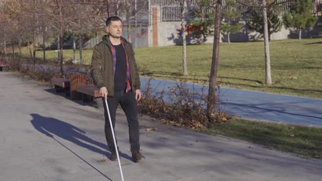 The-blind-man-walks-alone-on-the-road.-He-has-a-walking-stick.