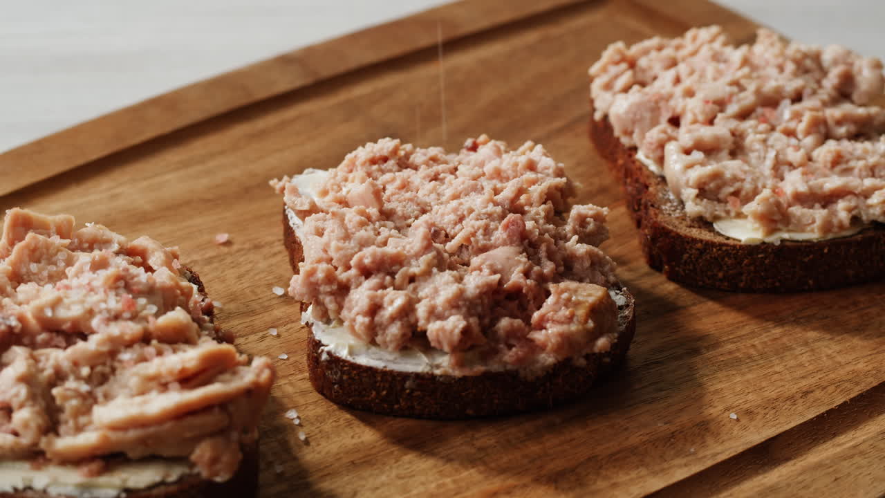 Smoked cod liver in oil in open tin can with fresh greens on wooden table. Seafoods delicacy. High quality 4k footage