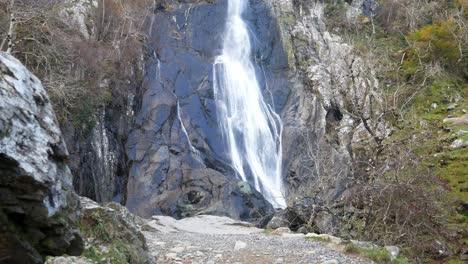 rocky cascading waterfall rushing into jagged river rocks dolly right from behind boulders