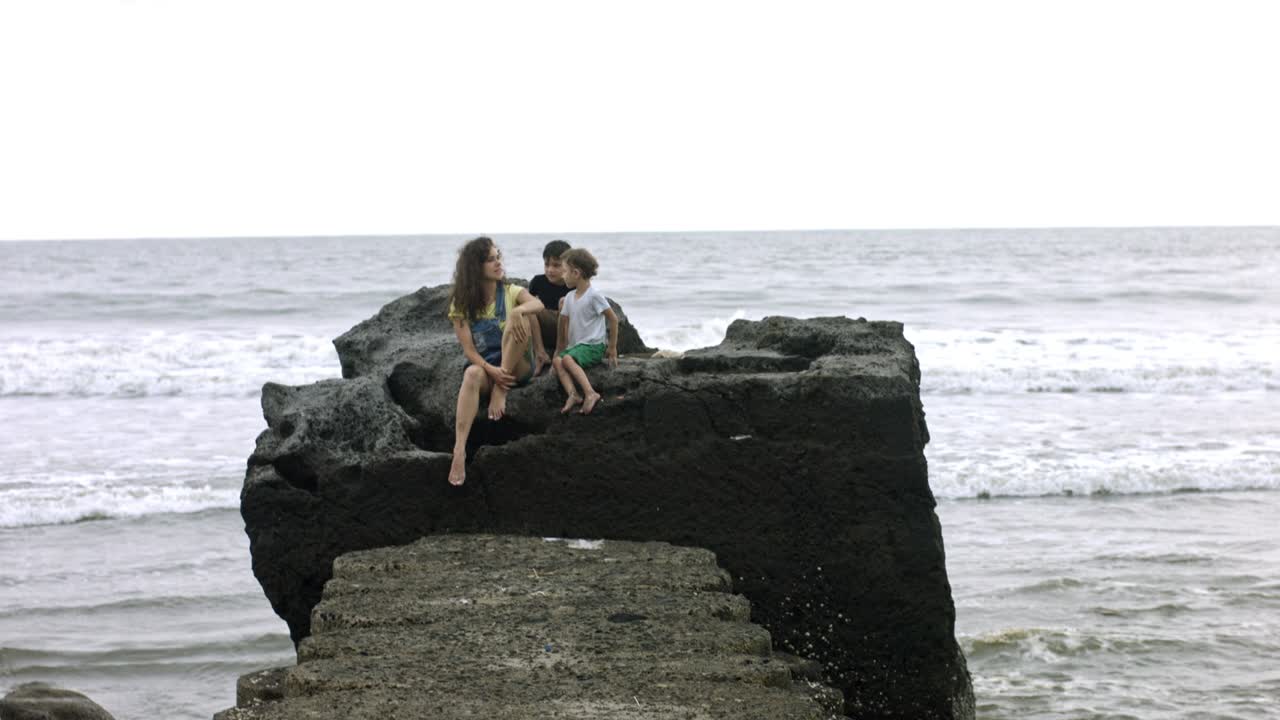 madre e hijos acurrucados en la playa