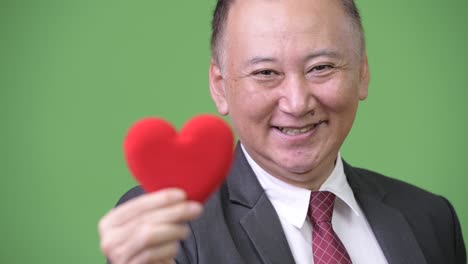 mature japanese businessman holding red heart ready for valentine's day