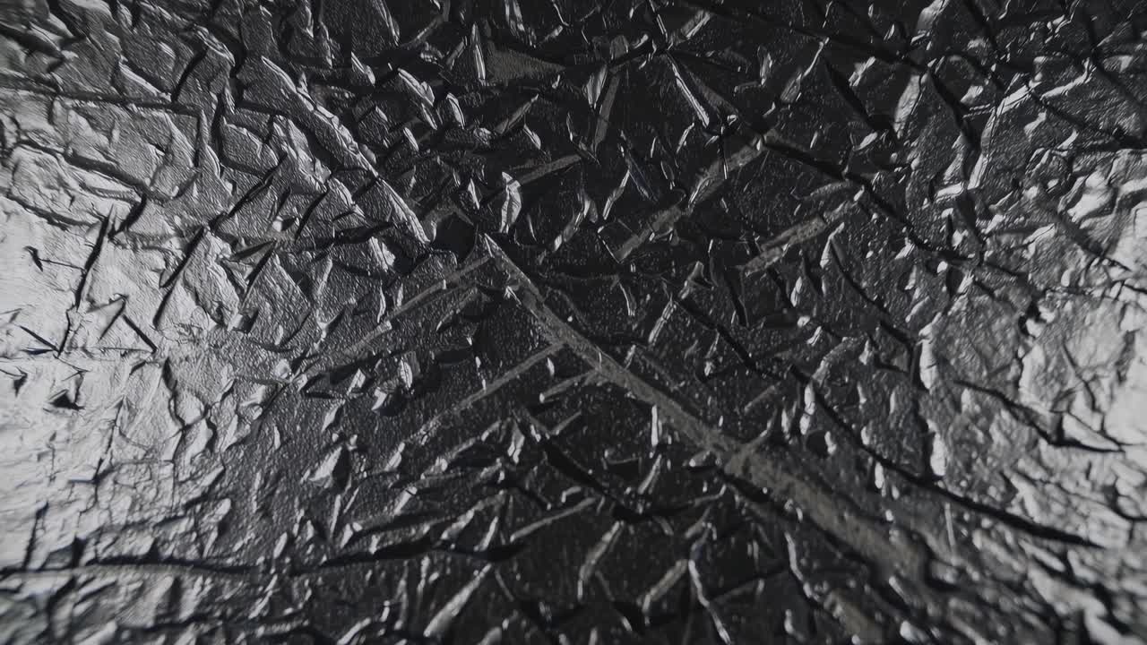 Close-up video of textured, cracked glass surface. Shot from above, the abstract pattern creates