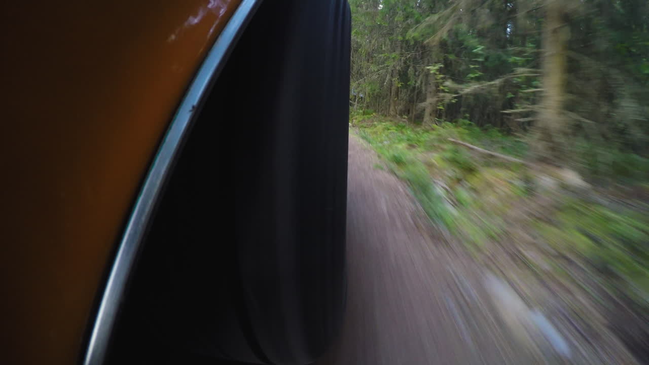 숲 속 비포장 도로에서 운전하는 동안 복고풍 자동차 바퀴의 4k 클로즈업
