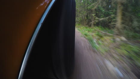 4k close-up of a retro car wheel while driving on a dirt road in a forest