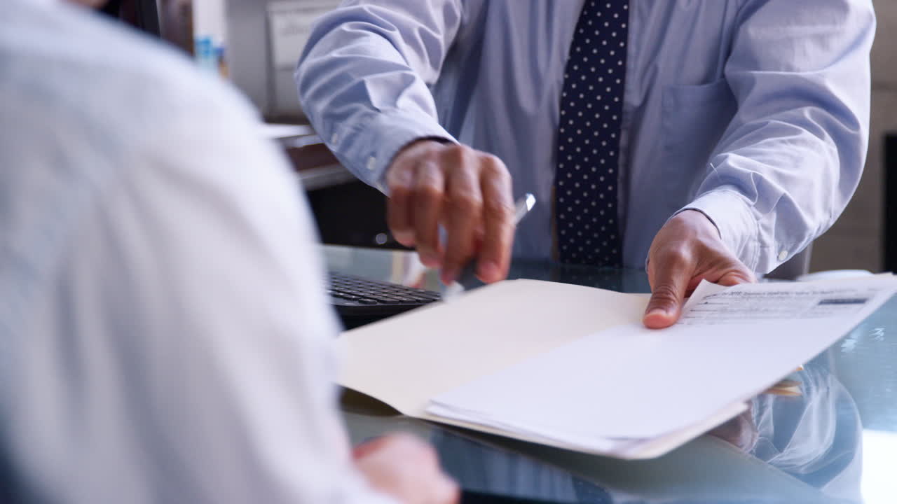 Businessman with male client signing paperwork in office