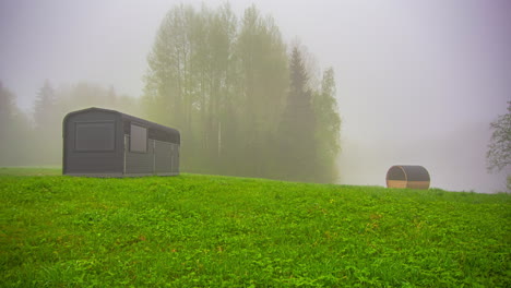 Fusion-clip-of-a-small-wooden-cottage-on-a-beautiful-rainy-landscape-with-rain-falling-at-different-times-on-different-parts-of-trees,-green-grass,-lake-and-wooden-cottage