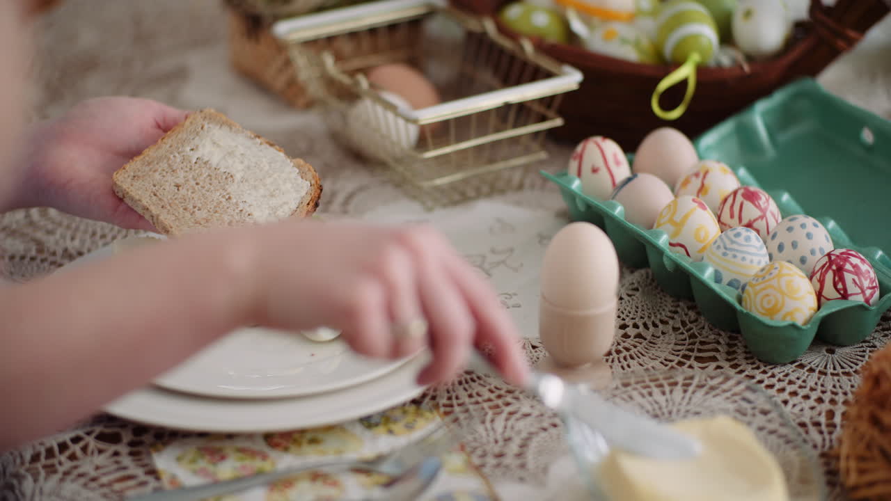 Hands Spreading Butter on Bread at Easter Breakfast Table