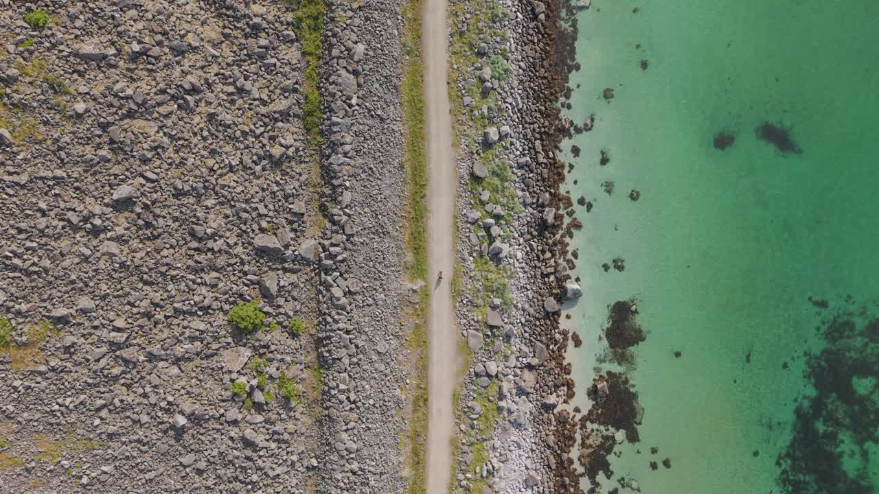 Bird's Eye View Of Person Biking On The Path Towards Hauklandstranda (Haukland Beach) In Lofoten Island, Norway. - aerial shot