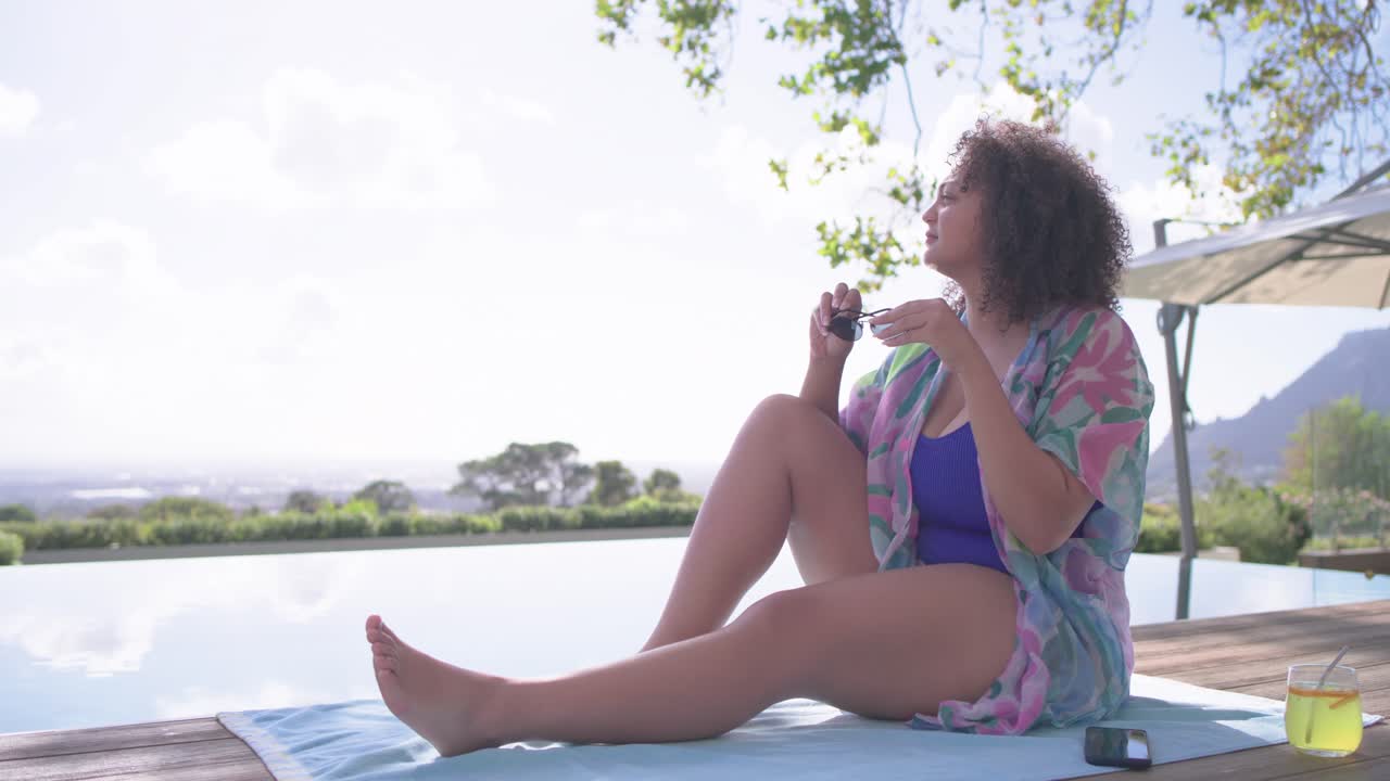 Sun urging African American woman sliding blue towel by pool taking cell donning shades, copy space