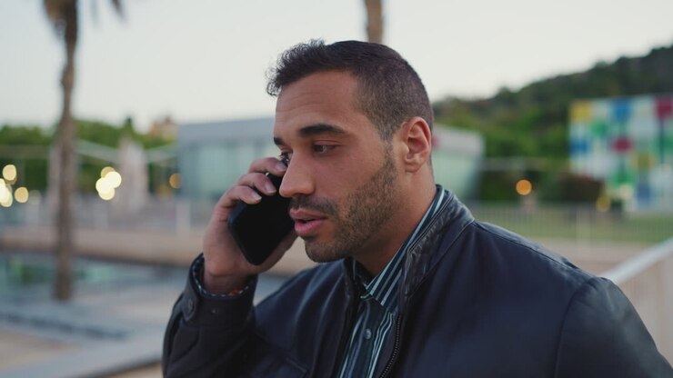 Young man calling on smartphone outdoors.