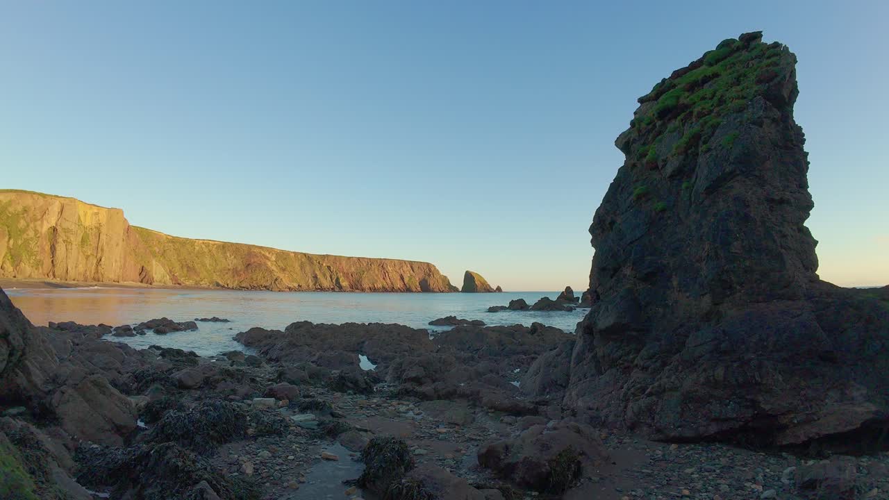 sea stack al atardecer con acantilados dorados y cielo azul claro ballydwane playa waterford irlanda