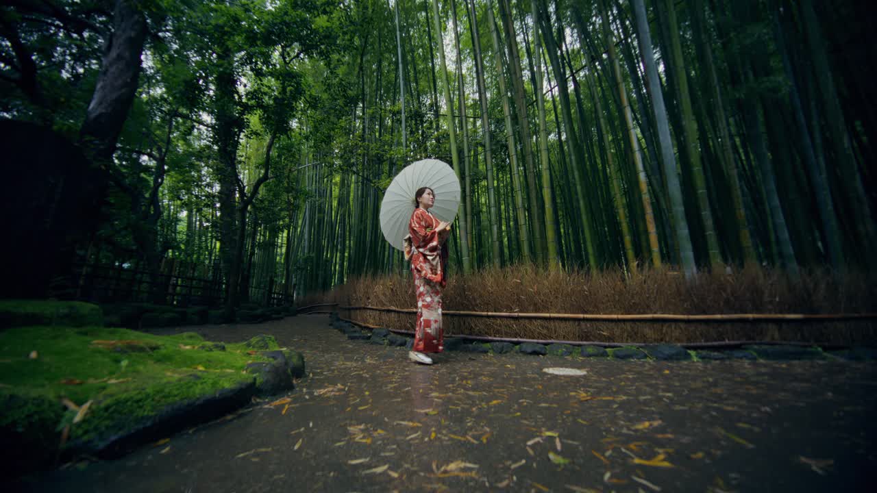 Donna in kimono che cammina in una foresta di bambù