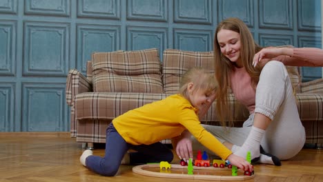 a young girl playing with a toy train with her mother