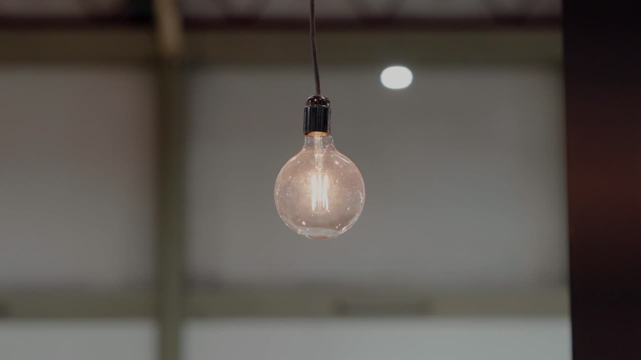 Single glowing lightbulb suspended in space, a symbol of bright ideas and classic design
