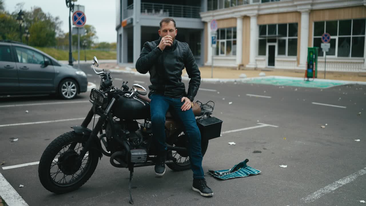 한 남자가 빈티지 모터사이클에서 커피를 마시고 있다