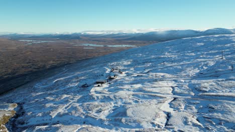 Glencoe-with-snow-covered-landscapes-and-isolated-buildings-in-winter,-clear-blue-skies,-aerial-view