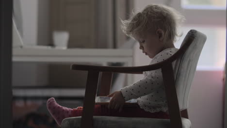 a baby girl sitting in a chair with a tablet on her laps