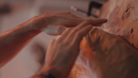 close-up of skilled artisan shaping intricate ridges in clay sculpture