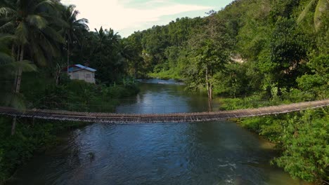 Exuberante-Paisaje-Tropical-Con-Un-Puente-Colgante-Sobre-Un-Río-Sereno-En-Bohol,-Día-Soleado