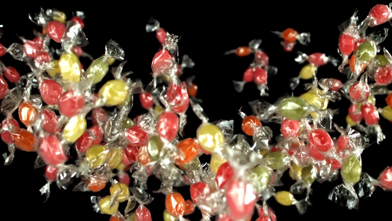 Doces Coloridos Embalados Flutuando em Fundo Preto em Câmera Lenta