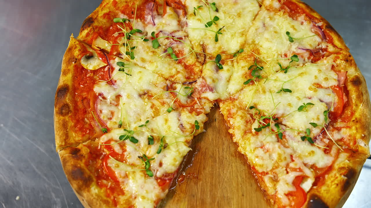 Fresh pizza spinning on the table. Delicious pastry with melted cheese, tomatoes and meat in pizzeria. Well baked pizza without one portion on table.