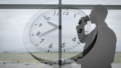 animation of clock with fast moving hands over caucasian businessman using smartphone at airport